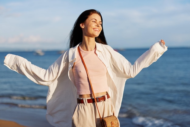 Mujer sonrisa libertad de vacaciones caminando en la playa junto al mar en Bali puesta de sol feliz viaje y vacaciones luz del atardecer