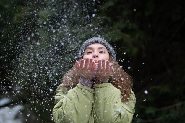 Mujer soplando nieve al aire libre sobre fondo de invierno. Concepto de felicidad y alegría. Foto de alta calidad