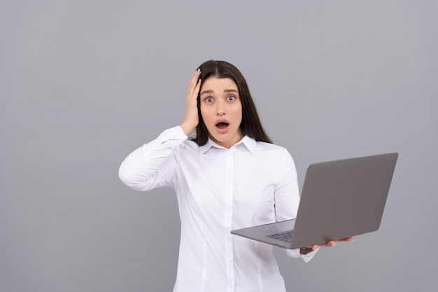 Foto la mujer sorprendida en la computadora del asimiento de la camisa blanca tiene mucho trabajo, exceso de trabajo.