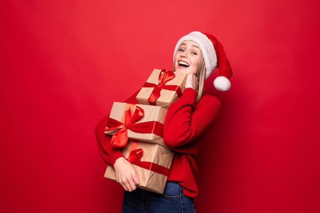 Mujer sorprendida emocionada en traje rojo de santa claus con pila presenta aislado en la pared roja