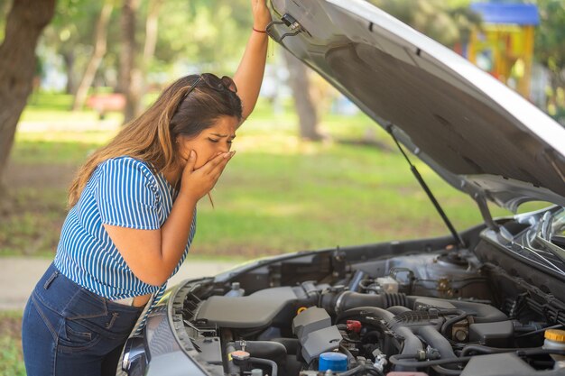 Foto mujer sorprendida por el olor de humo de su coche dañado levantando el capó para ver