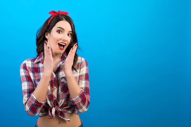 La mujer sorprendida de pie sobre el fondo azul.