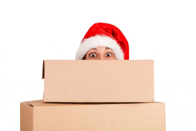 Mujer sorprendida en el sombrero de la Navidad que lleva a cabo el regalo de Navidad delante de la cara. aislado