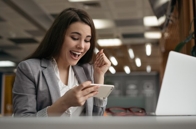 Mujer sorprendida sosteniendo teléfono móvil, comunicación, viendo películas