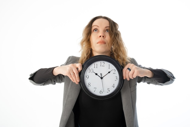 Foto una mujer sorprendida sostiene un gran reloj en sus manos sobre un fondo blanco.