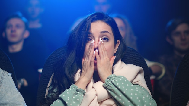 Mujer sorprendida viendo una película de terror en el cine Mujer asustada viendo una película de terror