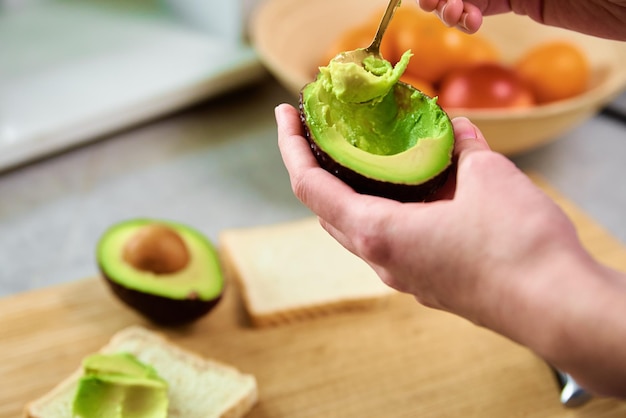 Mujer sostenga aguacate maduro fresco y pelarlo con una cuchara comida saludable y concepto de dieta orgánico pro