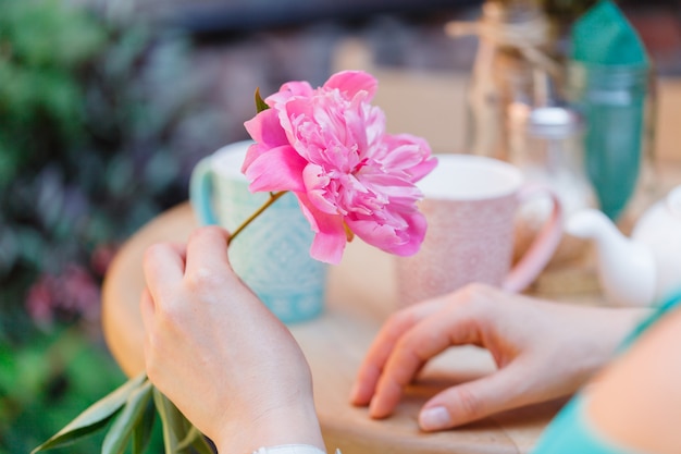 Mujer sostenga una flor de peonía en street cafe