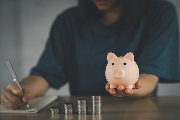 Mujer sosteniendo una alcancía rosa para aumentar el crecimiento del negocio para obtener ganancias y ahorrar con una alcancía Ahorrar dinero para el plan futuro y el concepto de fondo de jubilación