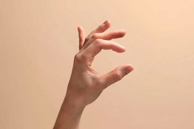 Mujer sosteniendo algo en la mano en primer plano de fondo beige Espacio para texto