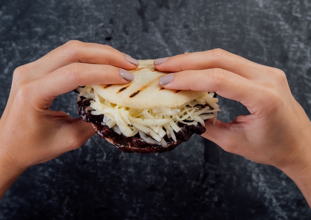 Mujer sosteniendo una arepa dominó.