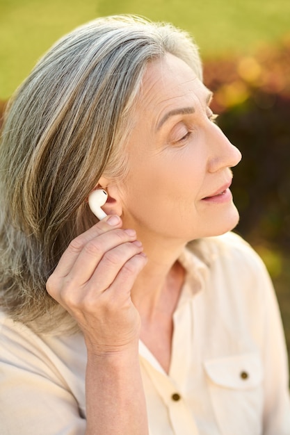 Mujer sosteniendo el auricular cerca de la oreja al aire libre