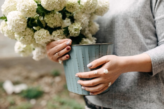 Mujer sosteniendo un balde con flores blancas de temporada