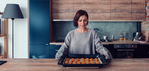 Mujer sosteniendo una bandeja para hornear con nuggets de pollo con respaldo