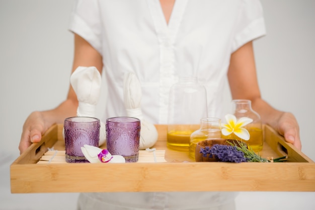 Mujer sosteniendo una bandeja con vasos y flores