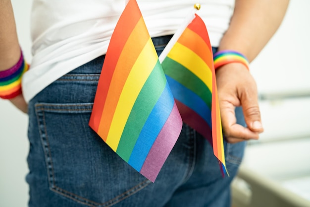 Mujer sosteniendo la bandera colorida del arco iris LGBT, símbolo de la paz y la tolerancia de los derechos humanos lesbianas gays bisexuales transgénero