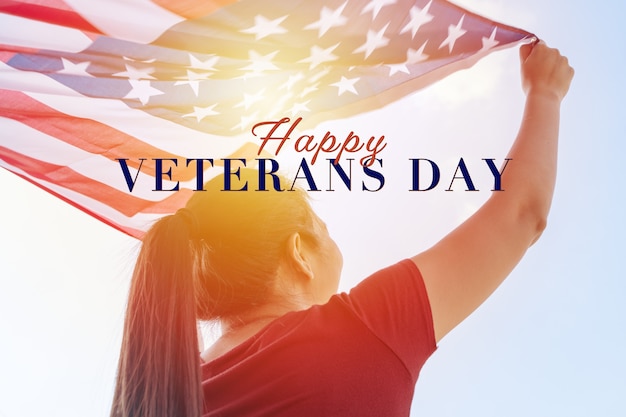 Foto mujer sosteniendo la bandera de los estados unidos de américa en el cielo soleado. día de los veteranos. honrando a todos que sirvieron.