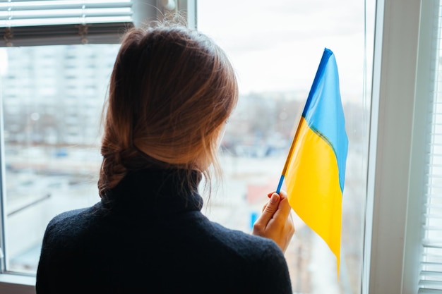 Mujer sosteniendo la bandera ucraniana durante la guerra con la invasión de rusia en ucrania ataque ruso de ucrania
