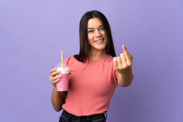 Mujer sosteniendo un batido de fresa haciendo próximo gesto