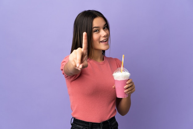 mujer sosteniendo un batido de fresa mostrando y levantando un dedo