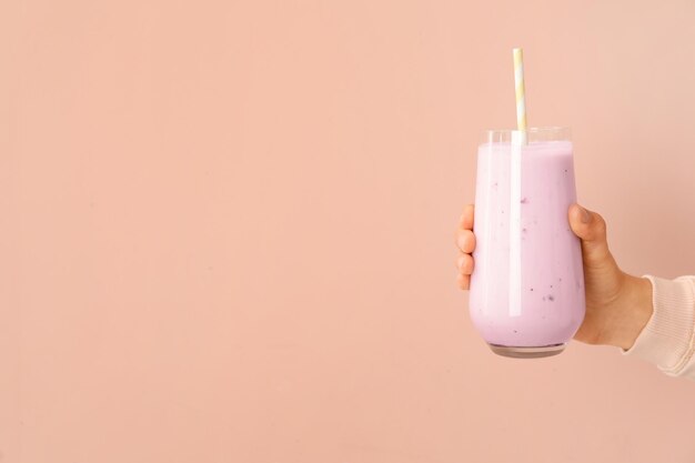 Mujer sosteniendo batido de higo sobre fondo rosa primer plano Espacio para texto