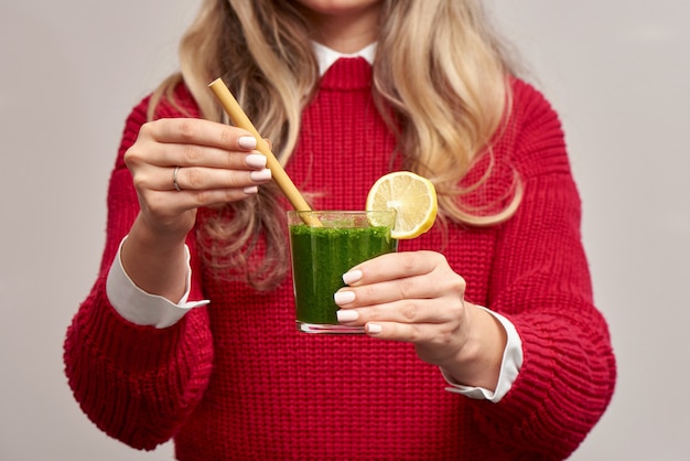 Mujer sosteniendo batido verde de espinacas frescas con paja de bambú