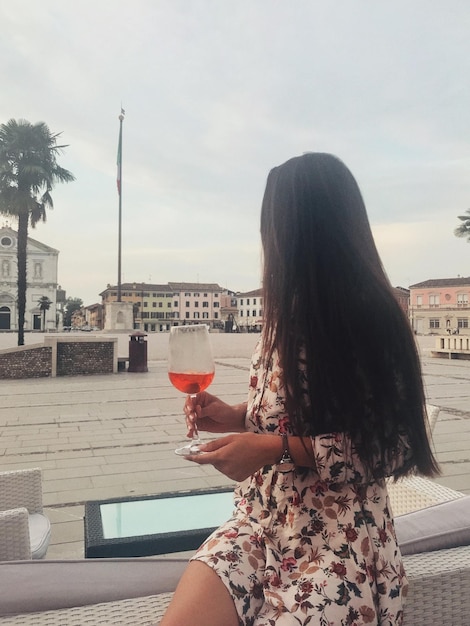 Foto mujer sosteniendo una bebida mientras está sentada en refresco