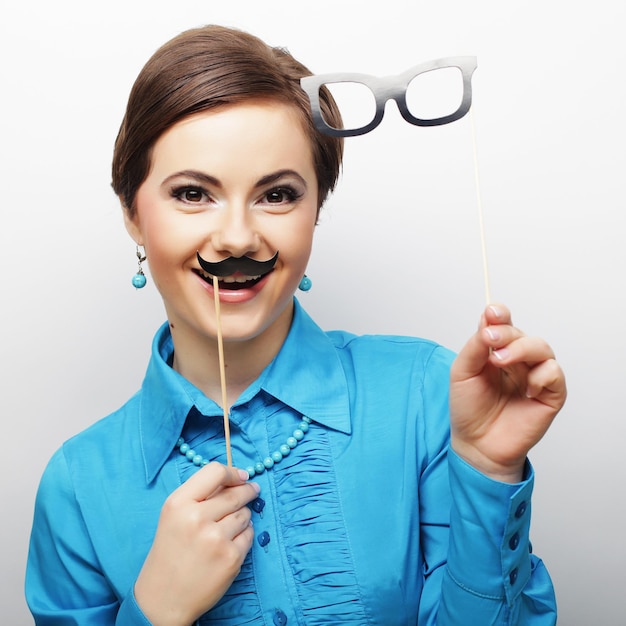 Mujer sosteniendo bigote y gafas en un palo