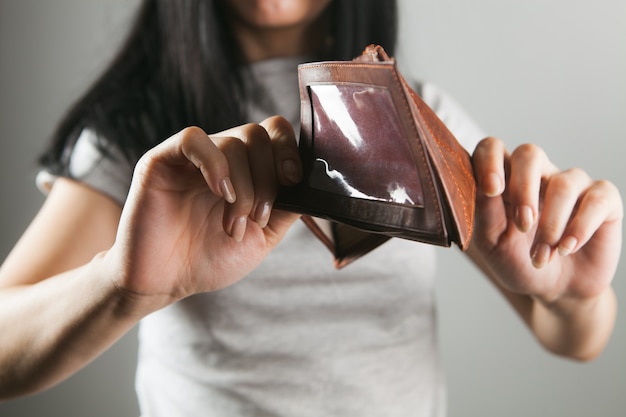 Mujer sosteniendo billetera de cuero vacía