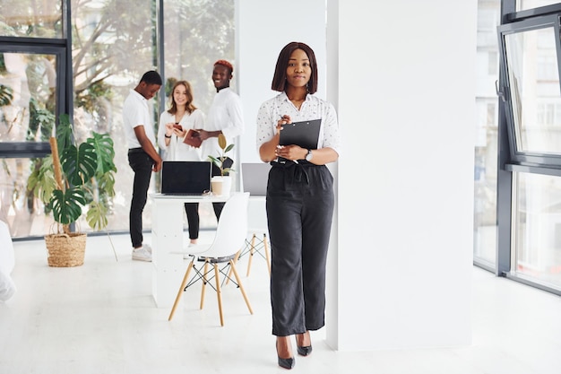 Mujer sosteniendo bloc de notas Grupo de empresarios afroamericanos trabajando juntos en la oficina
