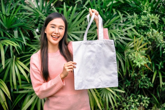 mujer sosteniendo una bolsa de algodón en blanco eco concepto de diseño de entorno maqueta