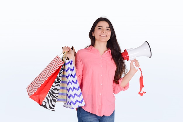 Mujer sosteniendo bolsas de compra y megáfono