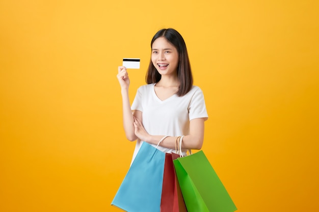 mujer sosteniendo bolsas de compras multicolores y tarjeta de crédito.