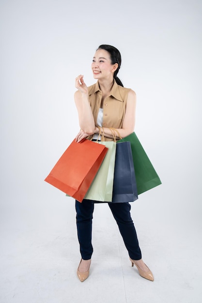 Mujer sosteniendo bolsas de papel con una sonrisa sobre fondo blanco en el concepto de compras.