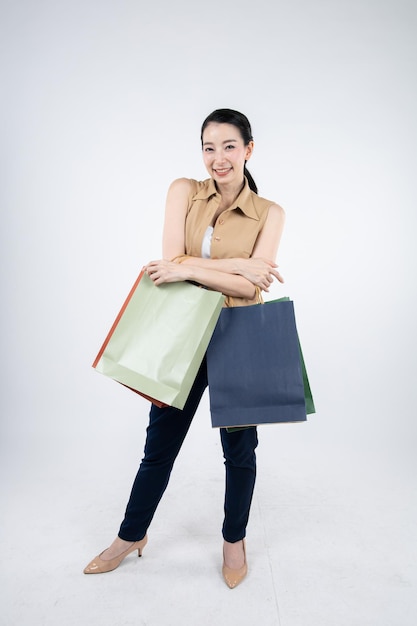 Mujer sosteniendo bolsas de papel con una sonrisa sobre fondo blanco en el concepto de compras.