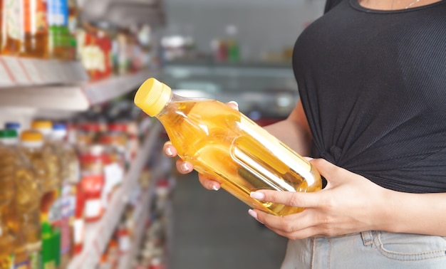 Mujer sosteniendo una botella de aceite de oliva en el supermercado.