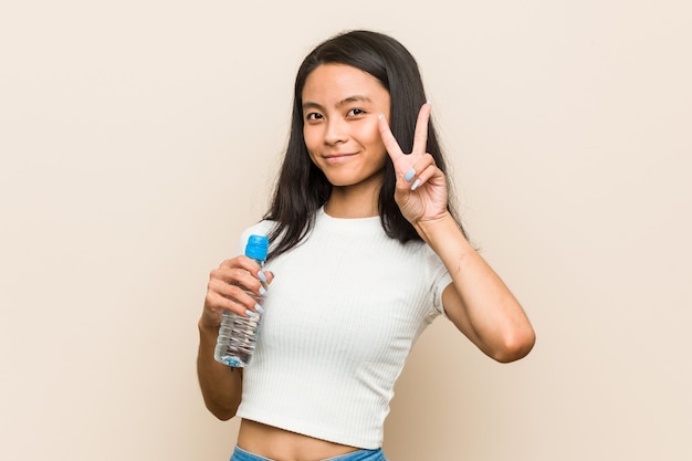 Mujer sosteniendo una botella de agua que muestra el signo de la paz