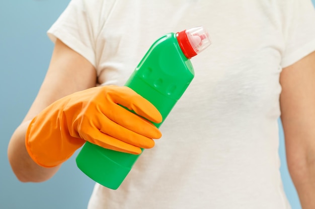 Mujer sosteniendo una botella de líquido de lavado sobre un fondo azul.