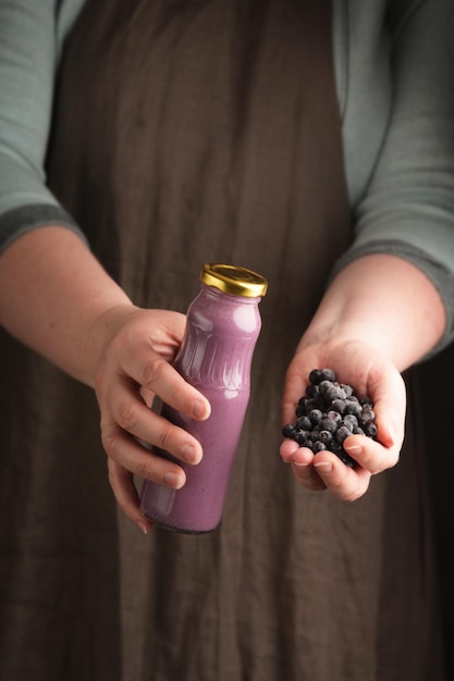 Mujer sosteniendo una botella de yogur y arándanos en la mano Estilo rústico