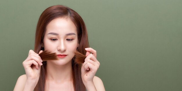 Mujer sosteniendo el cabello dañado la mano y mirando