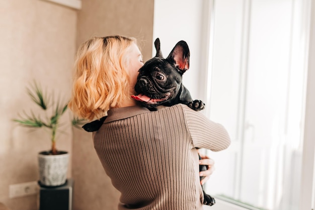 Mujer sosteniendo un cachorro de bulldog francés en sus manos lindo momento encantador del dueño amante de los perros Mascota feliz viviendo en el apartamento
