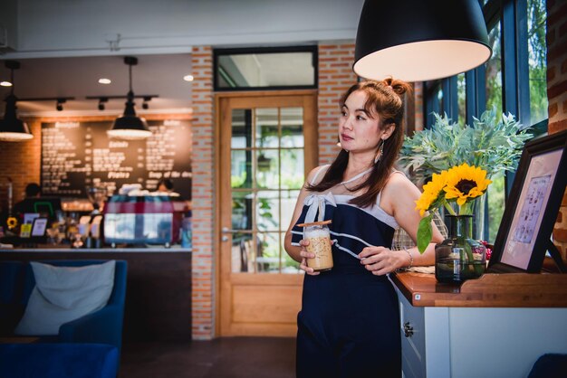 Foto mujer sosteniendo café mientras está de pie junto a la mesa en una cafetería