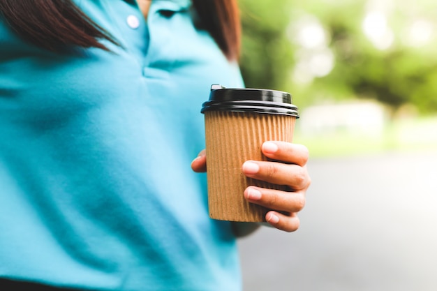 Una mujer sosteniendo café taza de papel.