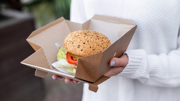 Mujer sosteniendo una caja de comida de papel reciclable con un sándwich. Idea de reciclaje