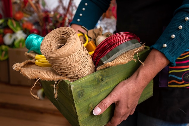 Mujer sosteniendo una caja de madera con herramientas en una florería