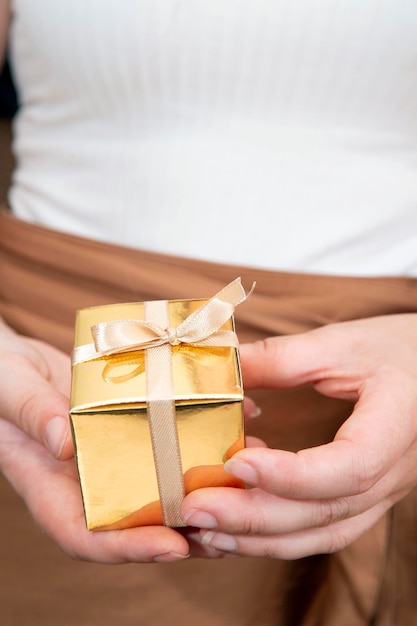 Mujer sosteniendo una caja de regalo de oro en un gesto de dar el día de la madre navidad concepto de regalo de cumpleaños ...