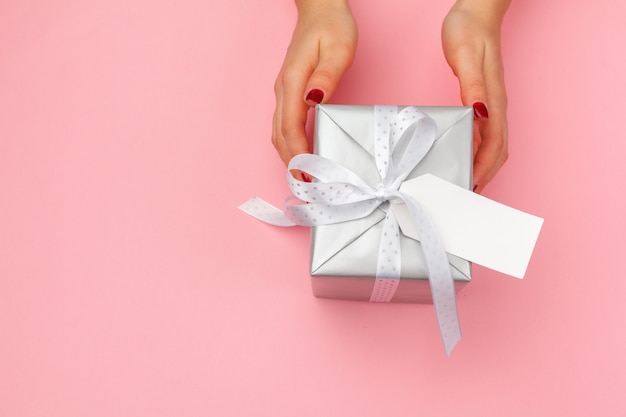 Mujer sosteniendo una caja de regalo en rosa