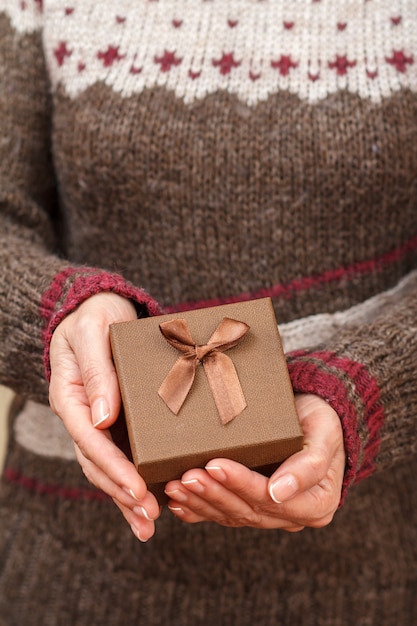 Mujer sosteniendo una caja de regalo en sus manos. Poca profundidad de campo, enfoque selectivo en el cuadro. Concepto de dar un regalo en vacaciones o cumpleaños.