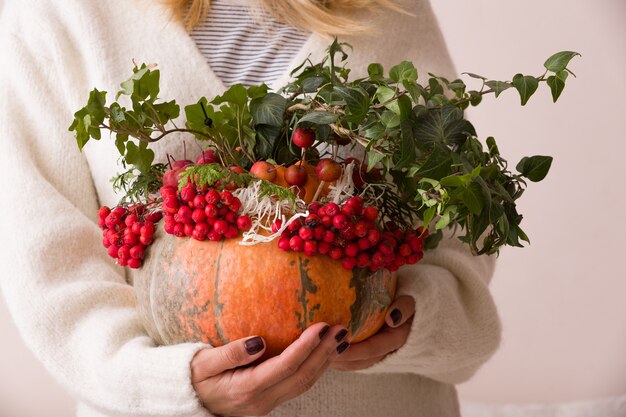 Mujer sosteniendo calabaza decorada para la mesa y celebración de Acción de Gracias de Halloween