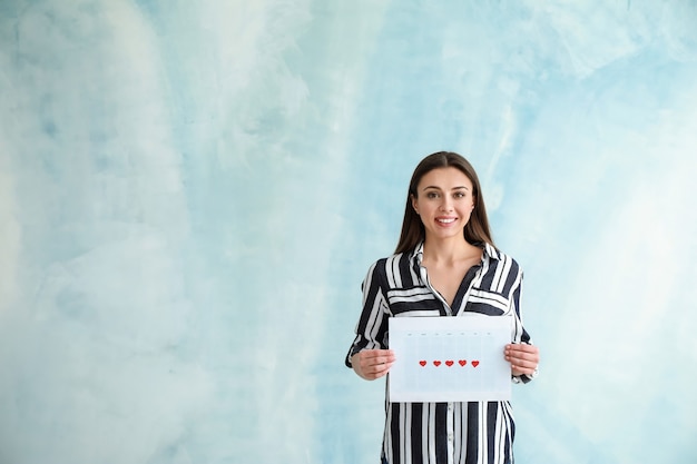 Mujer sosteniendo el calendario con los días marcados de la menstruación en azul